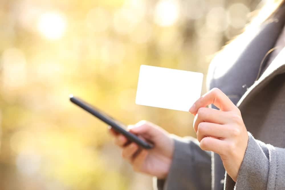 A woman holding a blank credit card in front of a Minnesota state campground.