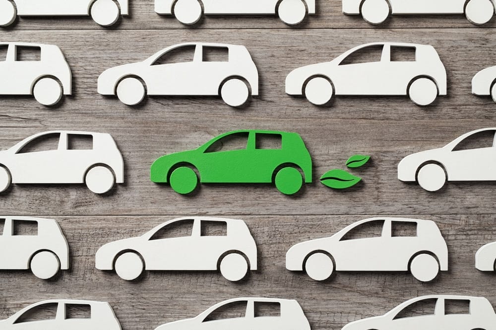 A group of green paper Campervan cars on a wooden background.