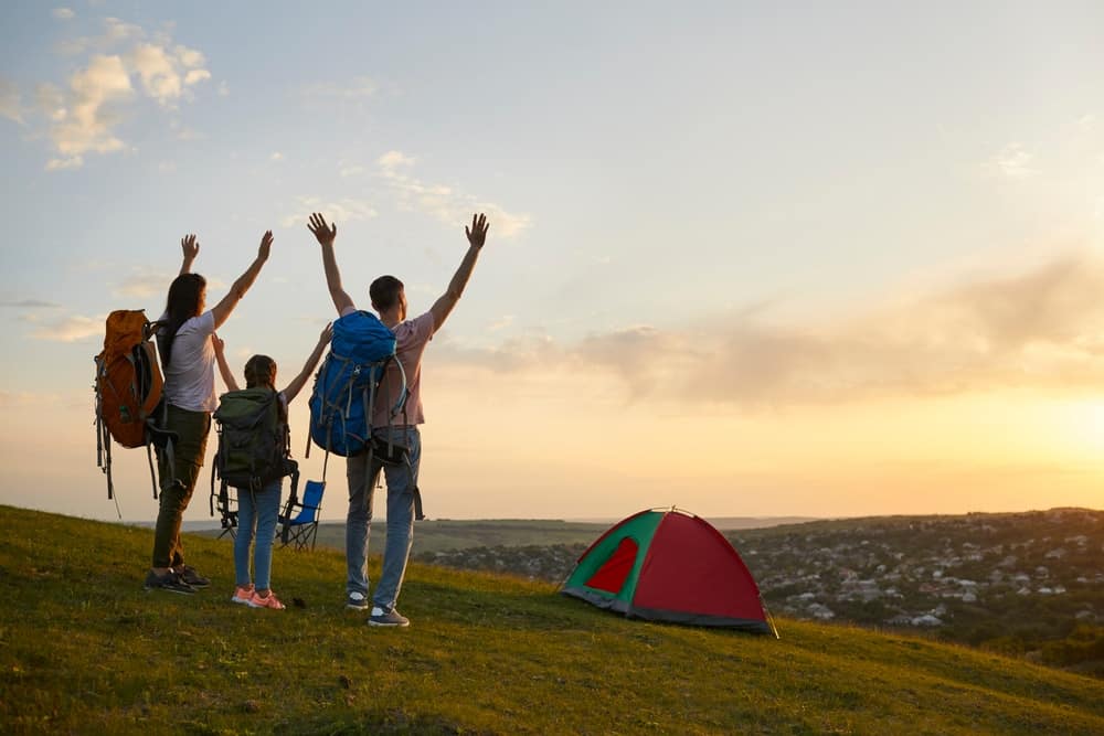 A family is enjoying outdoor activities on a hill, with a tent rising in the background.