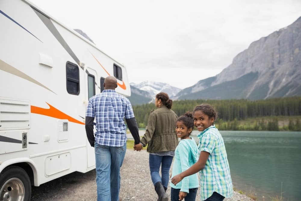 Family standing next to an RV in front of a lake, enjoying their Q1 2023 Results with Sun Communities that have exceeded expectations.