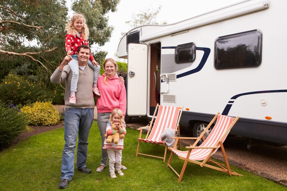 A Canadian family standing in front of an RV while enjoying camping.