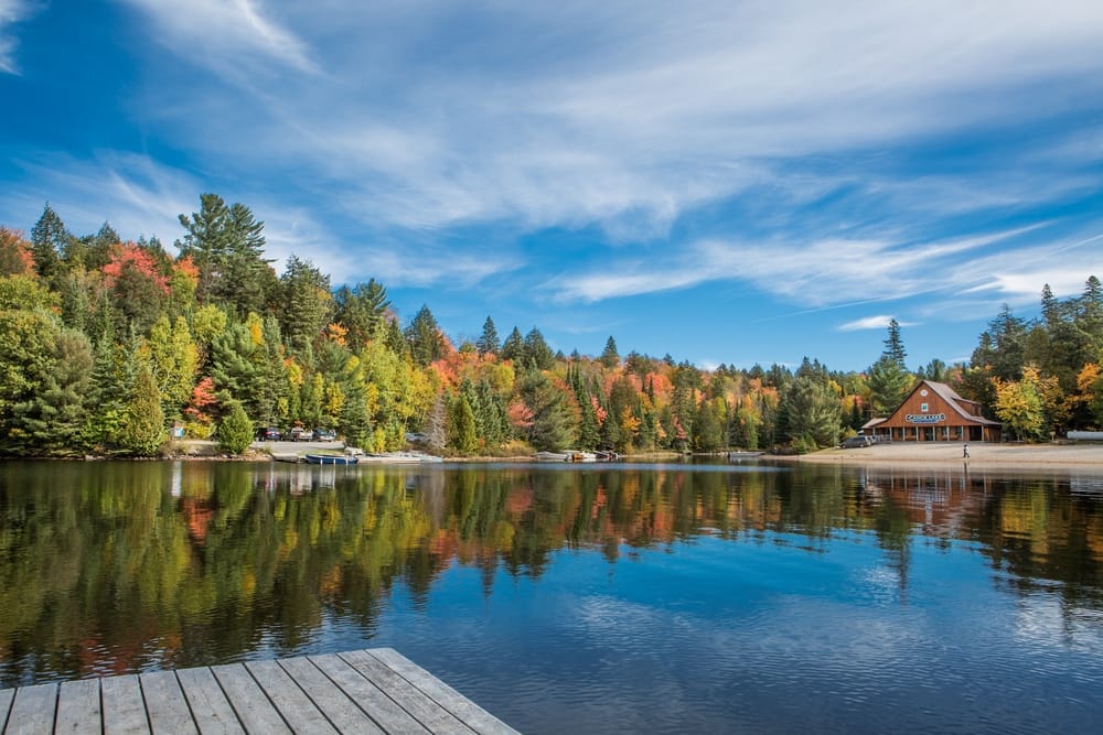 A serene lake surrounded by trees, complete with a rustic dock ideal for camping and located in the Ottawa Valley.