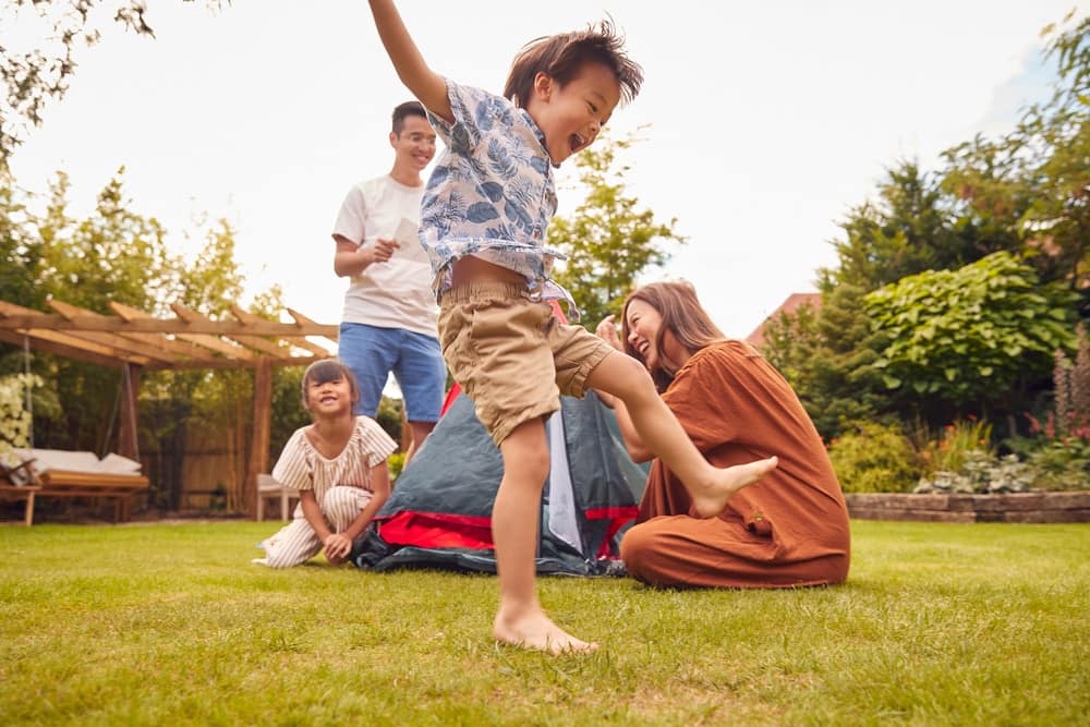 A family is enjoying outdoor activities in the backyard with a tent.
