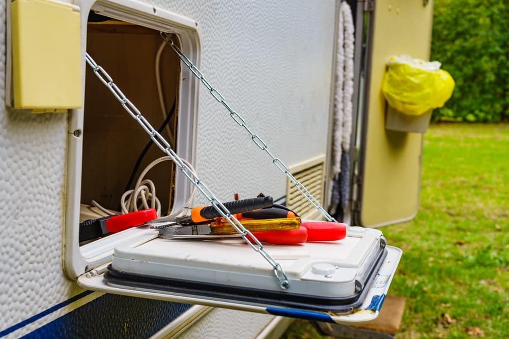 A camper trailer equipped with tools on the side of it, perfect for enthusiasts undergoing Tyson Watkins' Comprehensive Training Program at RVTI.
