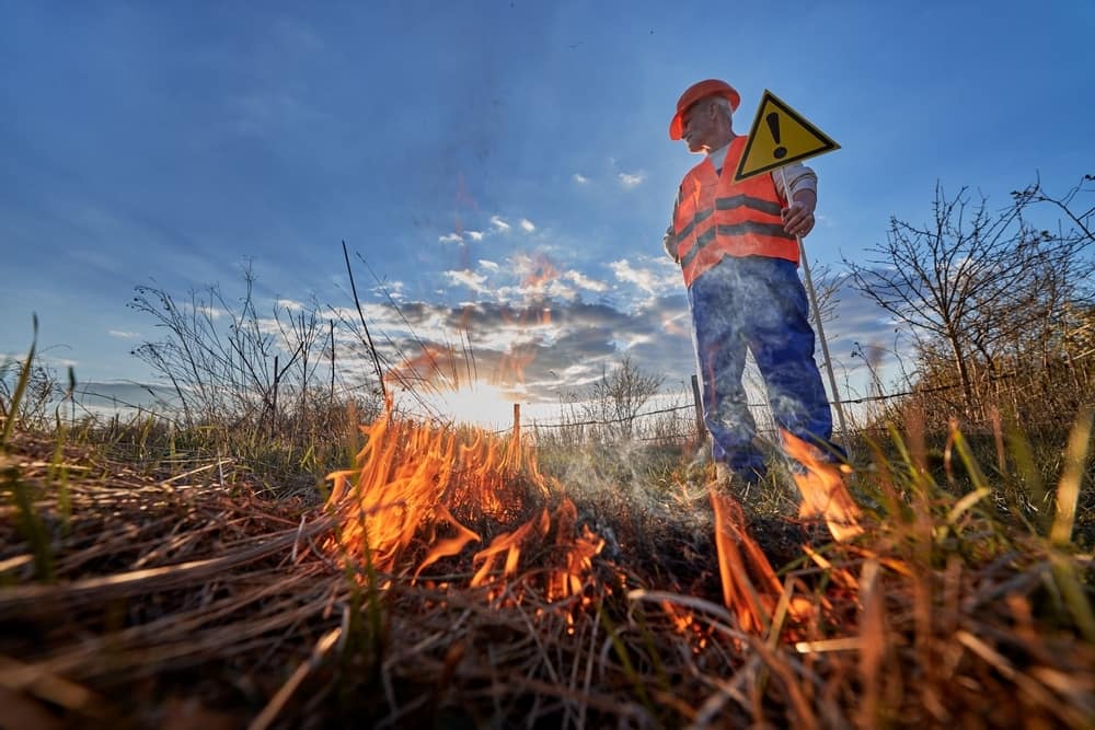 A worker in Alberta standing near a fire with a warning sign in parks.