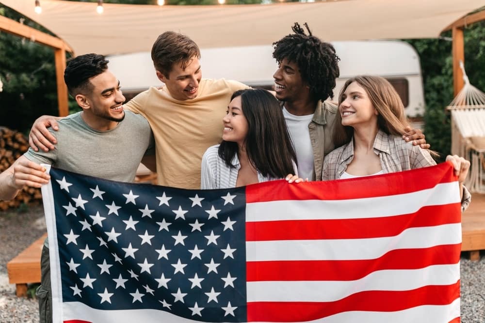 A group of friends holding an American flag during Memorial Day Weekend.