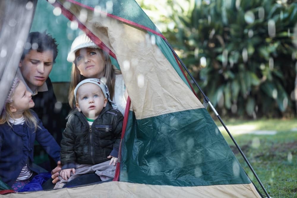 A family sits in a tent during a rainstorm.
