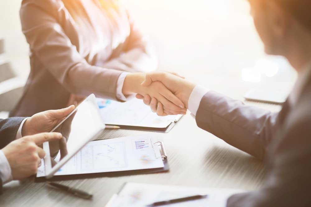Two business people shaking hands at a meeting to discuss the growth and leadership opportunities of Kampgrounds of America.