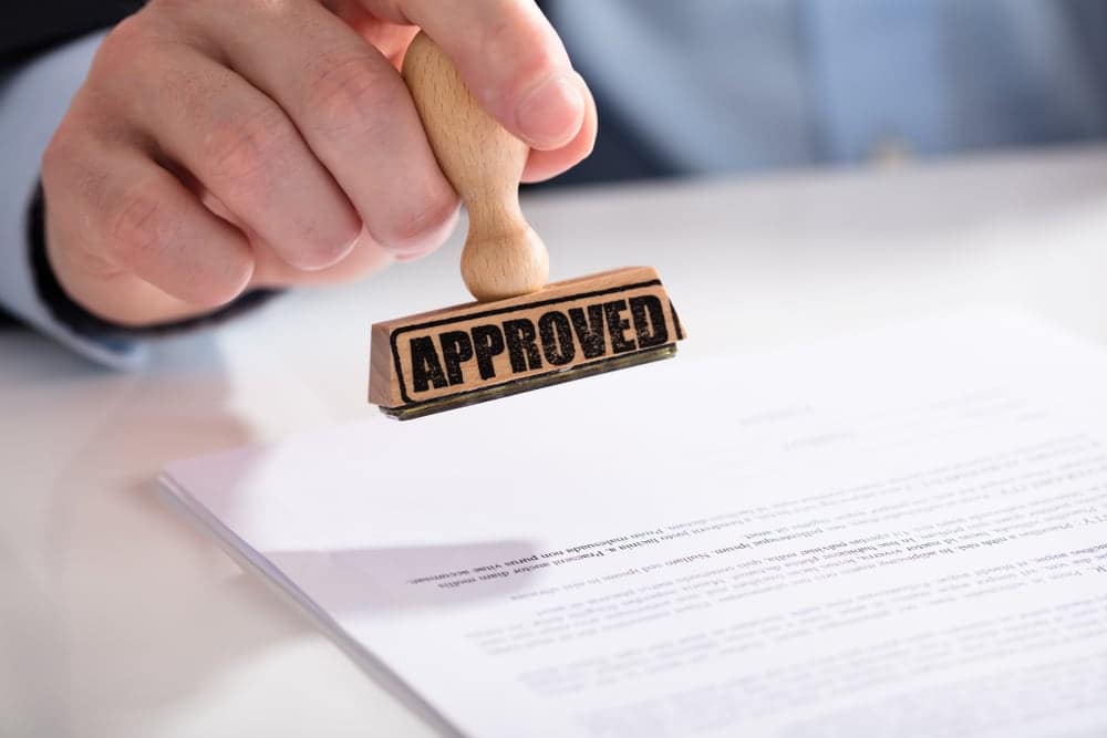 A man holding a rubber stamp with the word approved on it at a Year-Round Campground, giving Greenlights by the Anderson County Board.