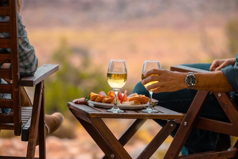 A couple enjoying a picnic at a winery in the desert with wine and food.