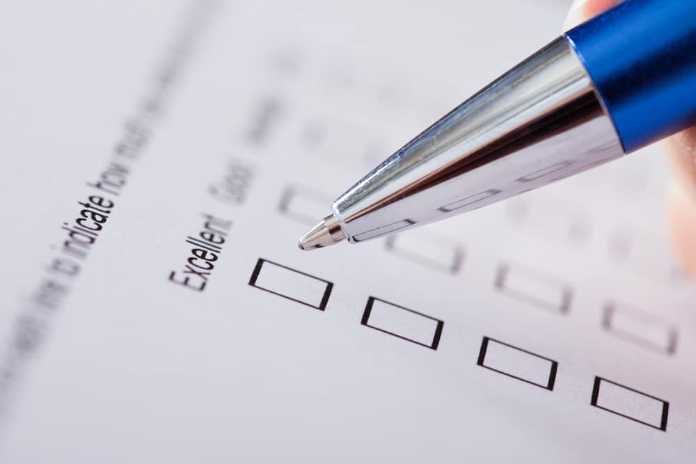 A person filling out a RVDA Dealer Satisfaction Index Survey form with a pen.