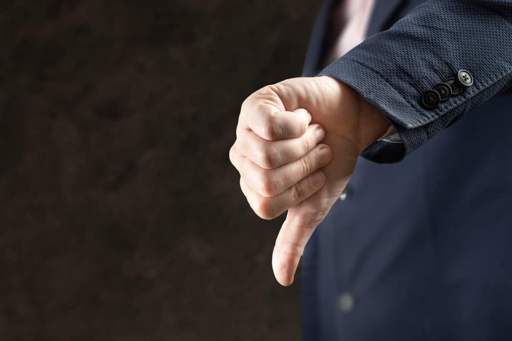 A man in a suit is making a thumbs down gesture at the Mason Zoning Board.