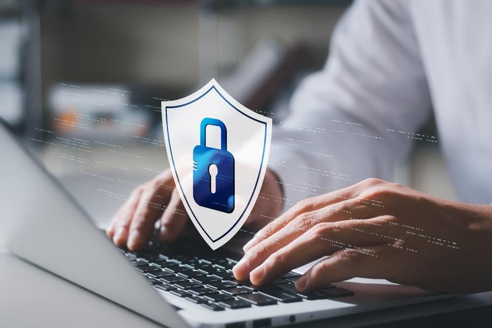 A man, with a SOC 2 Type 2 Certification, typing on a laptop with a padlock on it while using Campspot.