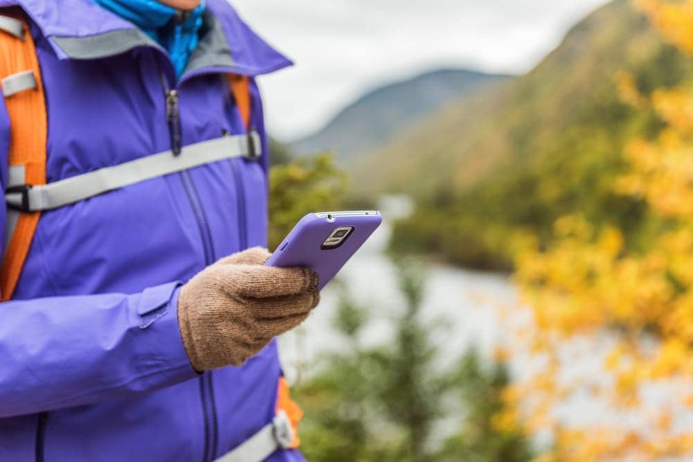 A woman in a purple jacket is holding a Simplify cell phone.