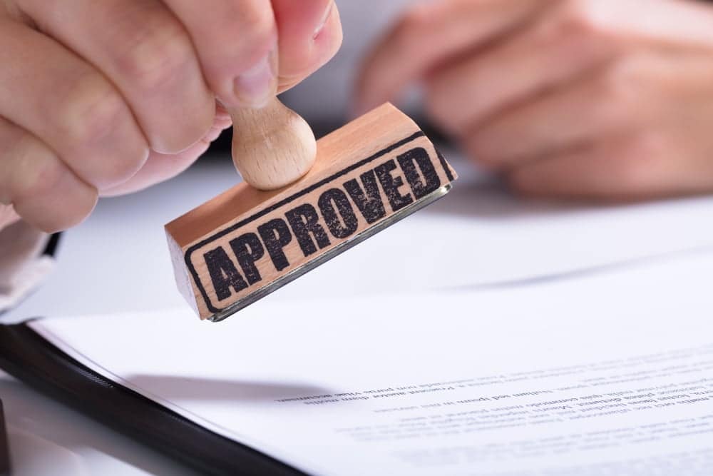 A person holding a rubber stamp with the word approved on it at a campground
