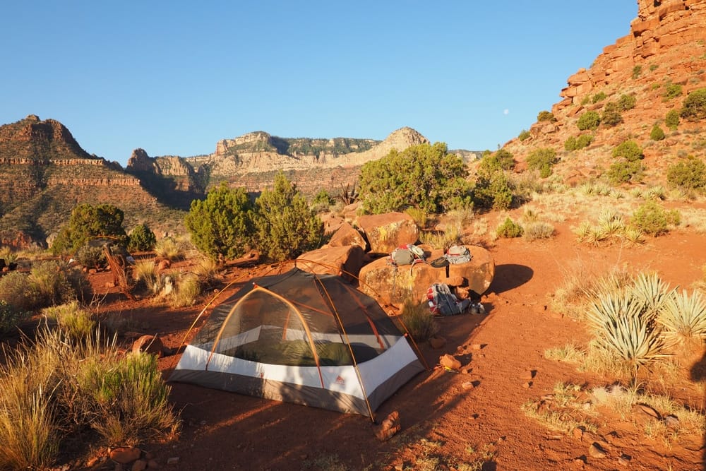 A tent in the Grand Canyon's desert landscape for Backcountry Camping, utilizing the National Park Service's 2024 Online Reservation Platform.
