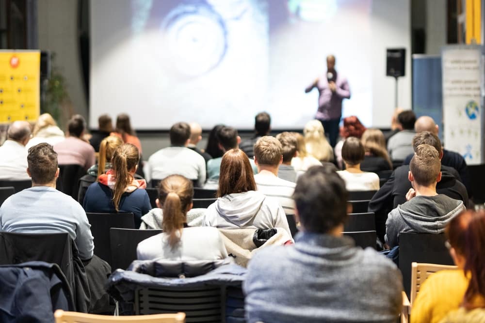 A man is giving a presentation to a group of people, aiming at improving trust between them.