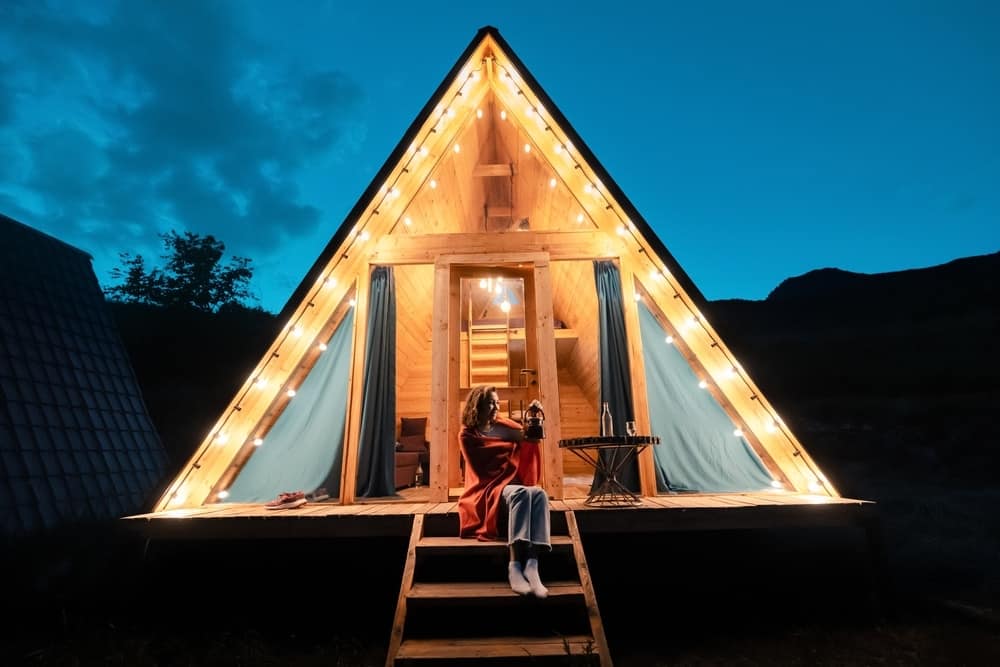 A woman enjoys the hotel-style comfort of a tiny house at night.