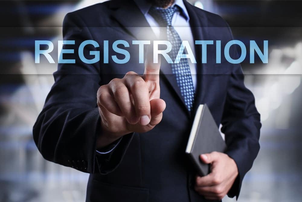 At the CONY Exposition, a man in a suit is enthusiastically pointing at the word registration during a trade show.