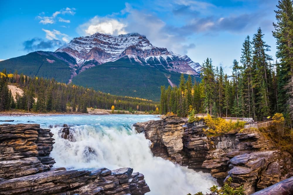 A picturesque waterfall in the mountains, enhanced by the presence of a majestic mountain in the background.