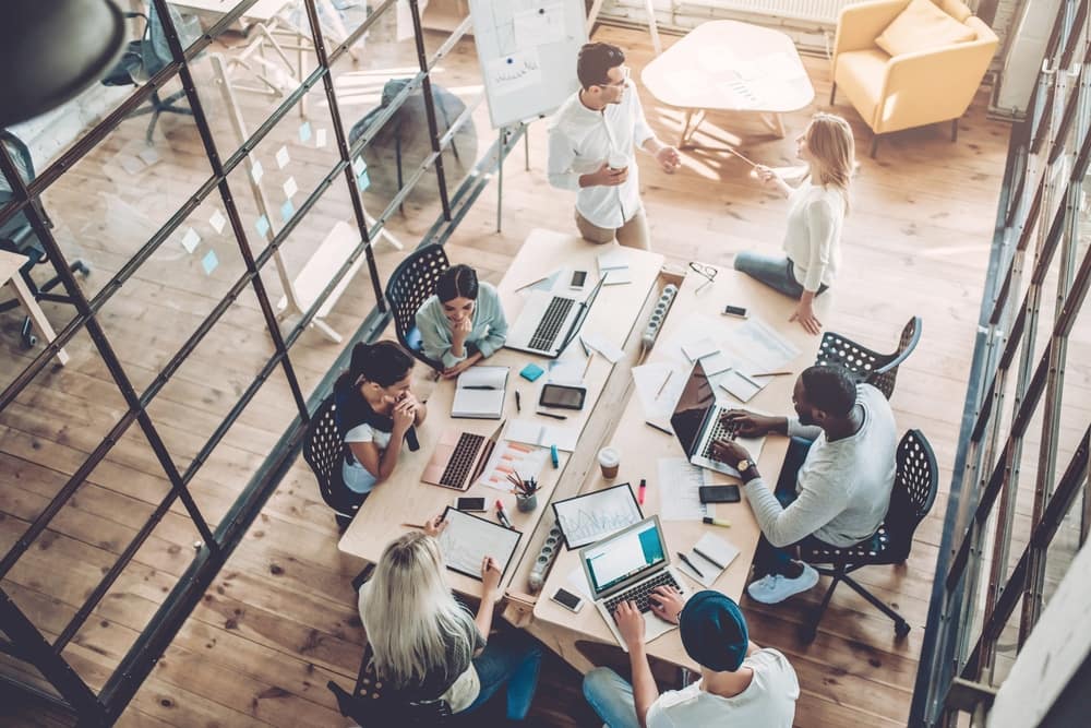 A group of people sitting around a table in an office, working together in the top workplace in Arizona.