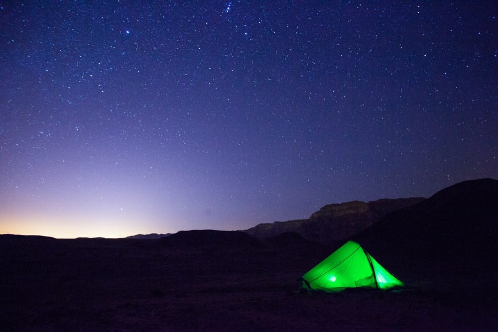 A green tent in the desert under a starry sky, illuminated by Lightspeed Team's SEO keywords.