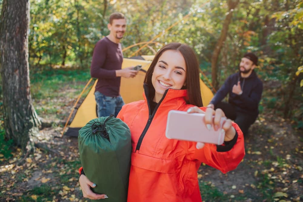 A group of people participating in a photo contest while camping in the woods.