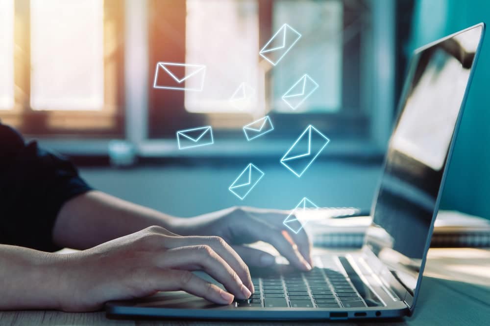 A person typing on a laptop with email icons flying out of it, showcasing remarkable success in an email campaign.