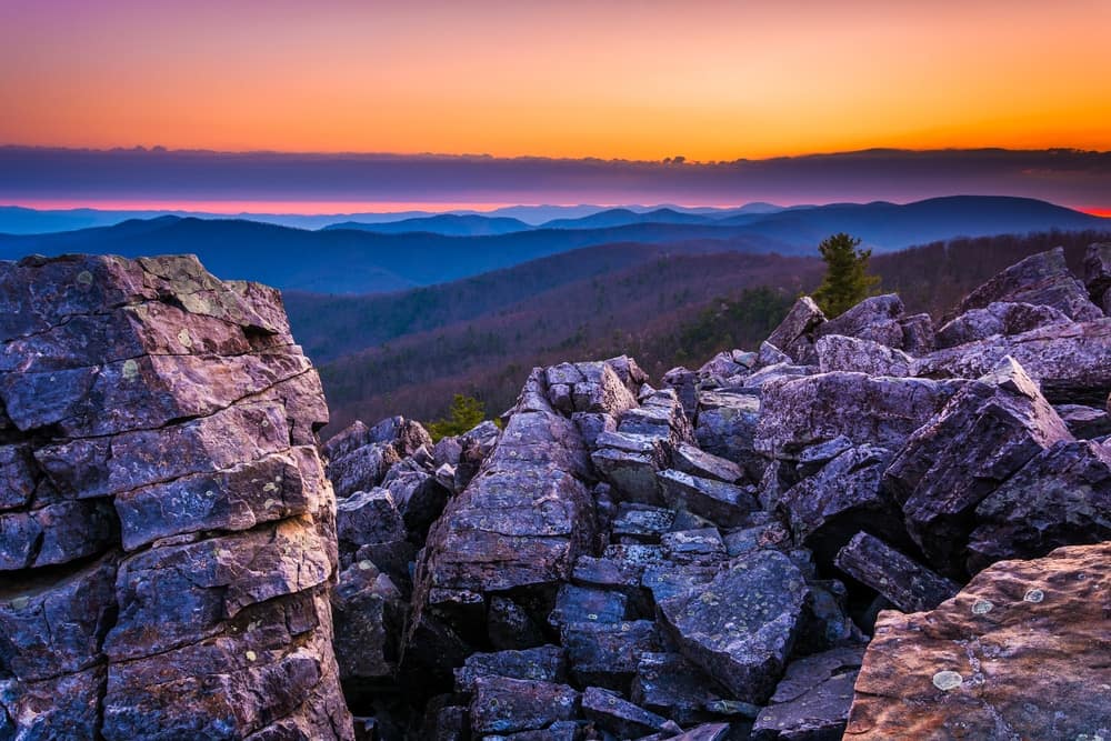 A sunset is seen from the top of a rocky mountain in a National Park.
