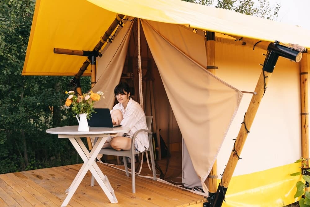 A woman sitting at a table in a tent in New England with a laptop.