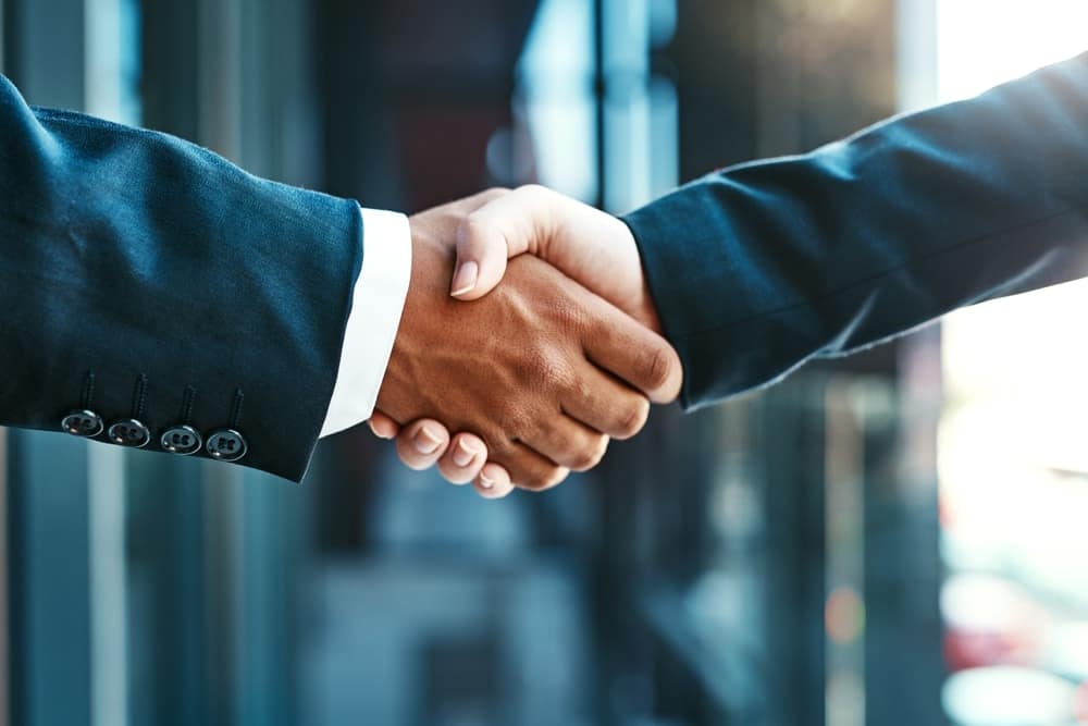 Brad Blakey, Revenue Manager at IVEE Management Group, shaking hands with another business person in front of a building.