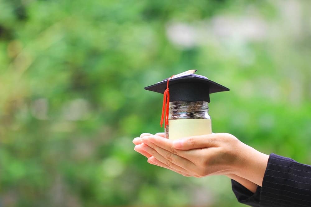 A woman's hand holding a graduation cap, symbolizing the achievement of receiving a Mason Upperman College Scholarship from the Mike Molino RV Learning Center.