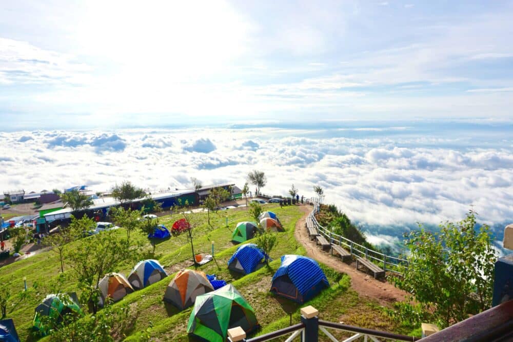 A group of tents set up on a hill overlooking the clouds in Southeast Asia.