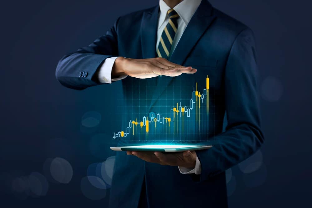 A businessman holding a tablet with a stock chart on it, showcasing the impressive growth of CRR Hospitality, ranked on the Inc. 5000 list.