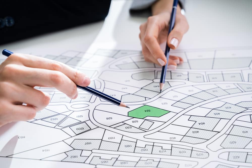 Two people working on a plan for a New Location development with pencils.