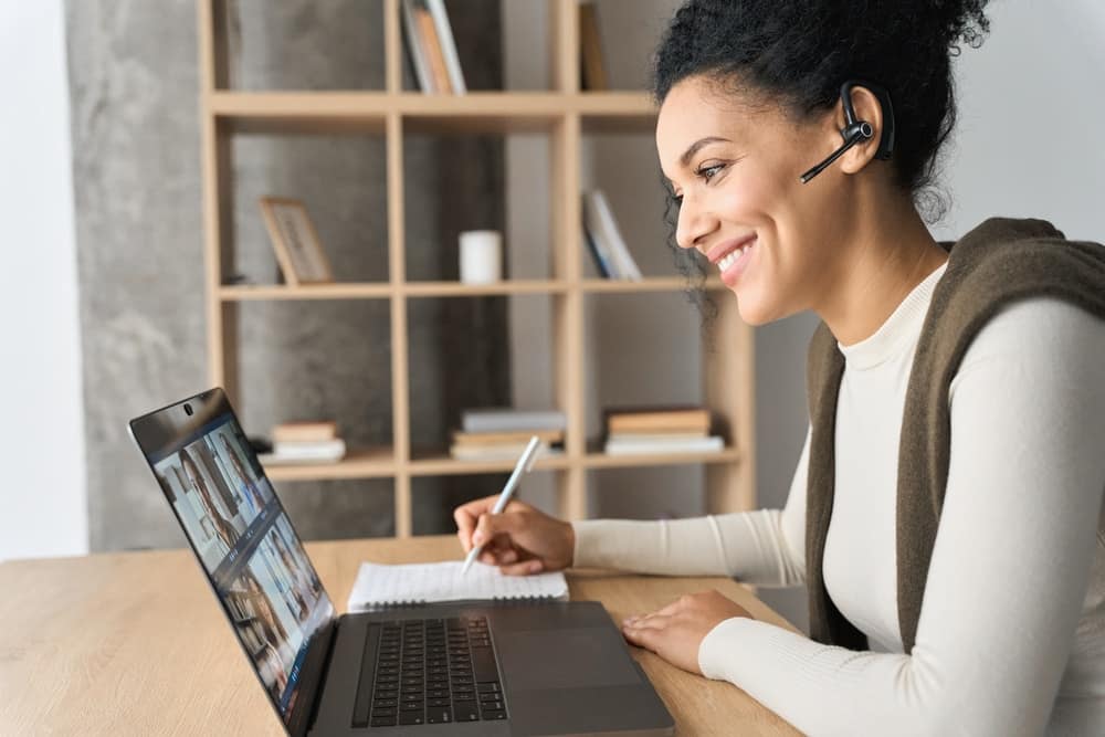A woman participating in a webinar while working on a laptop.