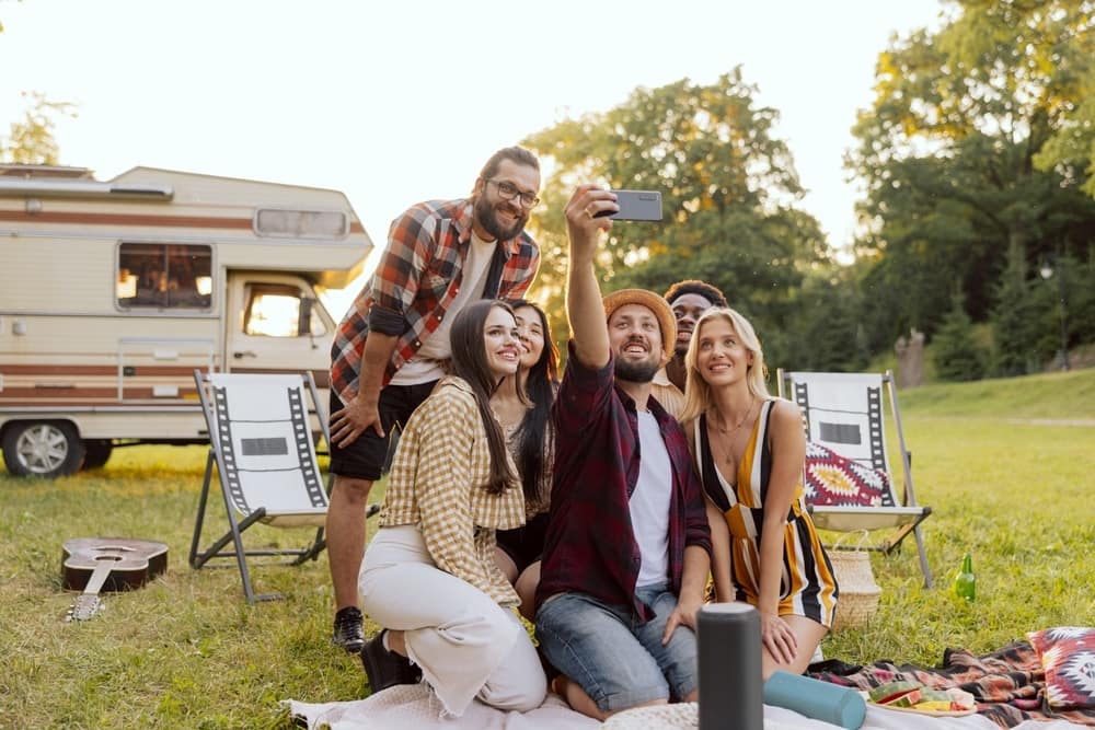 A group of friends taking a selfie in front of an RV.