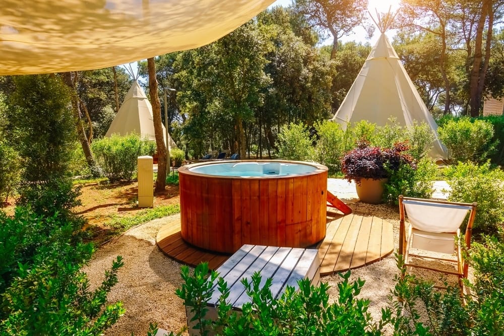 Profitable glamping sector featuring teepee tents and hot tubs in a garden.