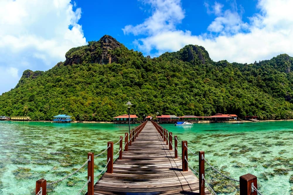 A Malaysian wooden pier leading to a tropical island, attracting tourism.