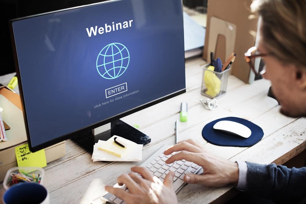 A man working on a computer, participating in a webinar to Stay Informed on the latest topics.