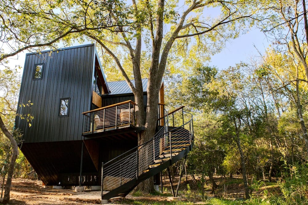 A nature-focused hospitality brand launches a tree house in the woods with a spiral staircase.