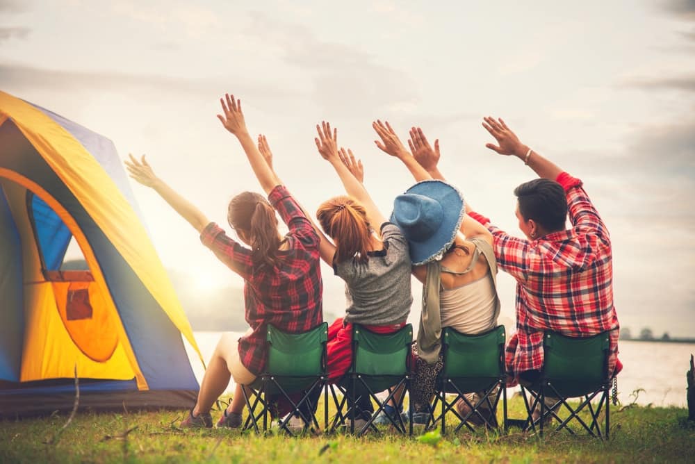 A group of people with their hands raised in front of an extended tent at Tofino Campground.