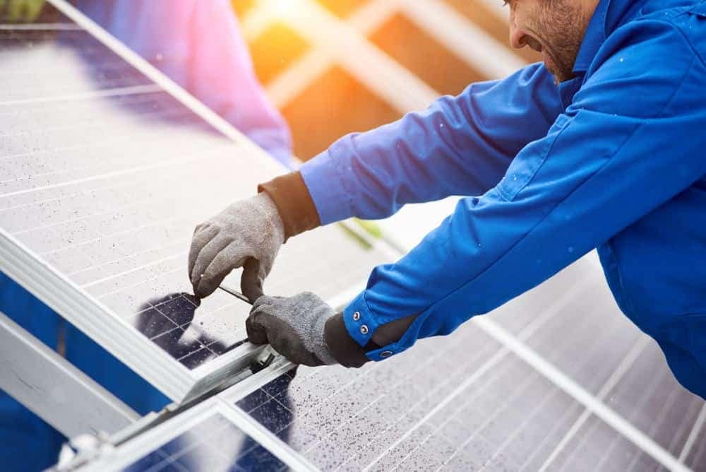 A man is installing solar panels on a rooftop in Holland.