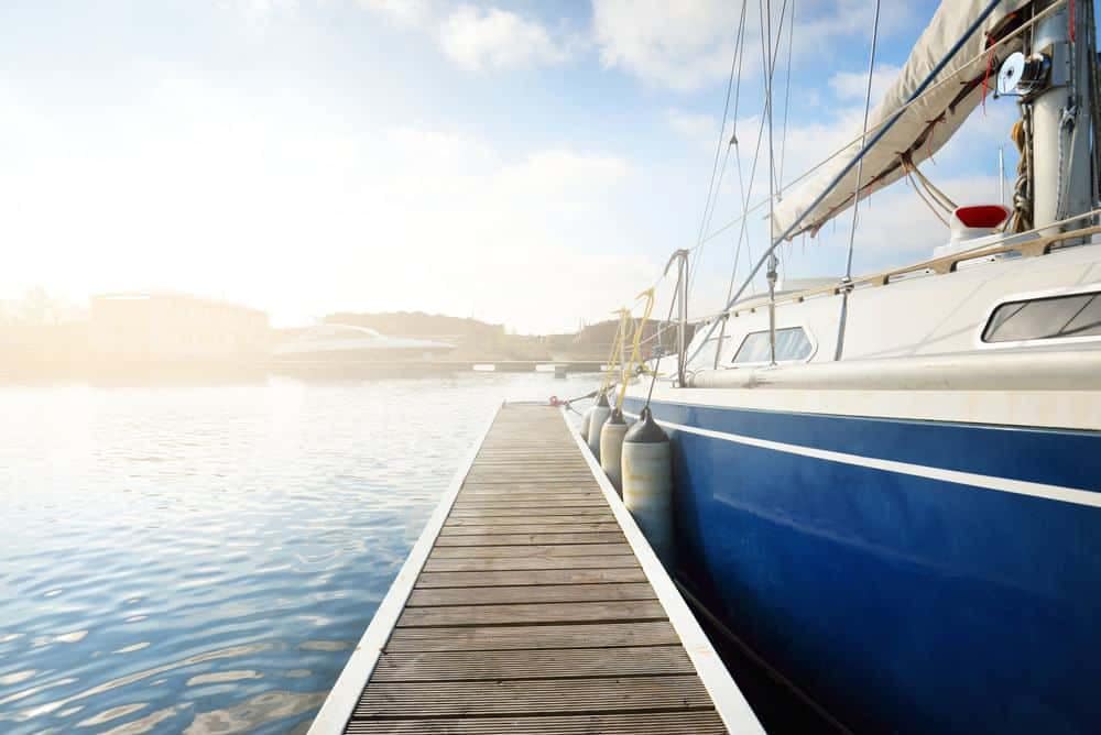 A blue and white sailboat docks at a marina.