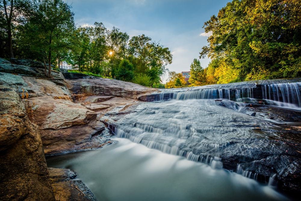 A picturesque waterfall nestled amidst a lush wooded oasis, offering a serene escape for tourists and contributing to South Carolina's economic recovery.