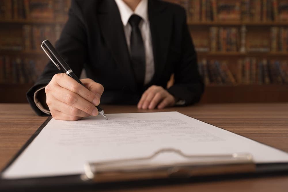 A business woman signing a document at a desk to ensure liability protections for campground operators in accordance with House Bill.
