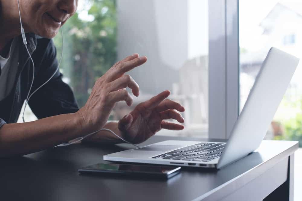A man is using a laptop while listening to music during a Zoom meeting.
