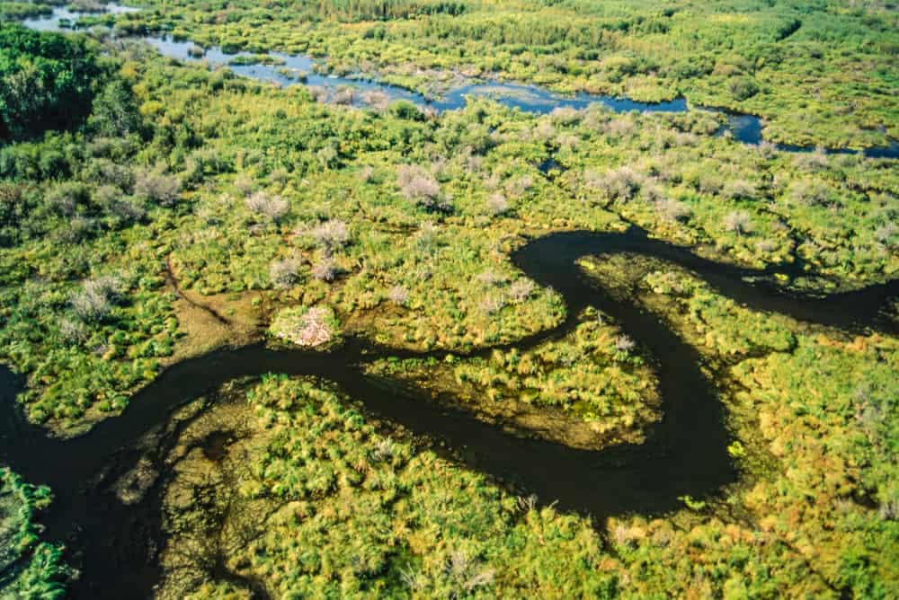 An overland flooding situation in Manitoba reveals an aerial view of a river cutting through a swamp, just in time for the seasonal campground opening.