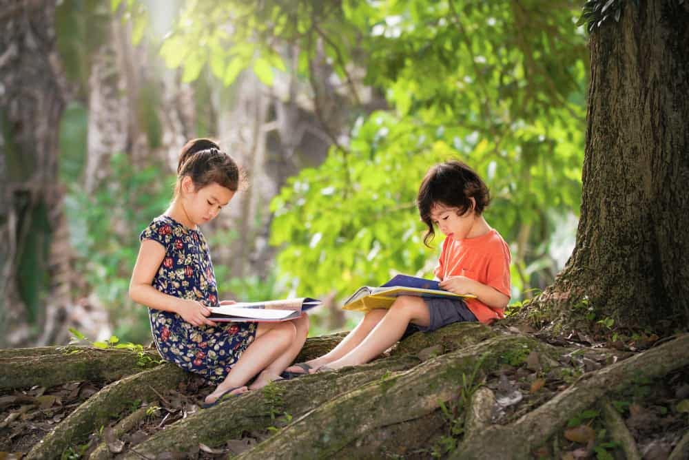 Two children are sitting on the ground reading books in Ohio's Barkcamp State Park.