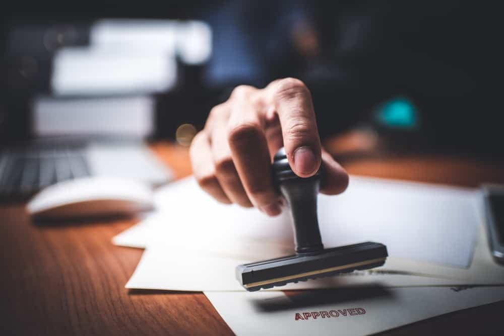 A hand is holding a rubber stamp on a piece of paper at Gun Lake Campground.